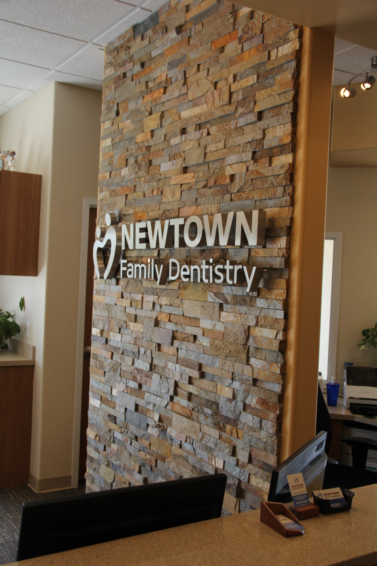 Two Sided Stacked Stone Feature Wall in Dentist Office with Stainless Steel Signage